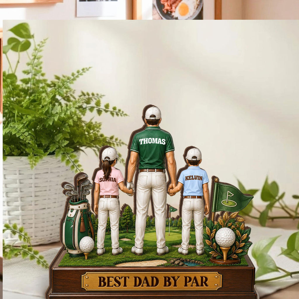 May include: A wooden golf-themed figurine featuring a father and two children holding hands. The father wears a green shirt with "Thomas" on the back. The children's shirts have the names "Sophia" and "Kelvin." The base reads "BEST DAD BY PAR."