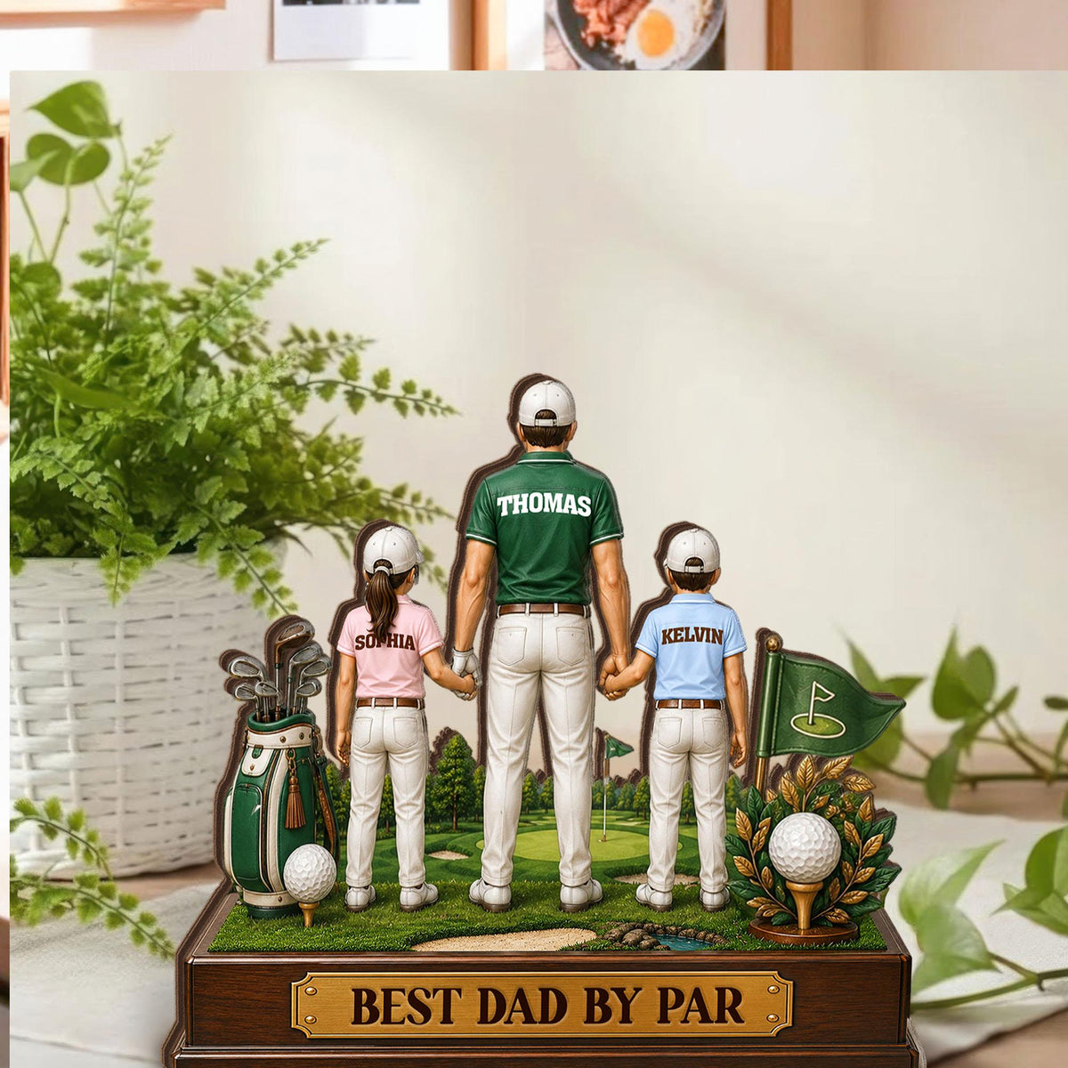 May include: A wooden golf-themed figurine featuring a father and two children holding hands. The father wears a green shirt with "Thomas" on the back. The children's shirts have the names "Sophia" and "Kelvin." The base reads "BEST DAD BY PAR."