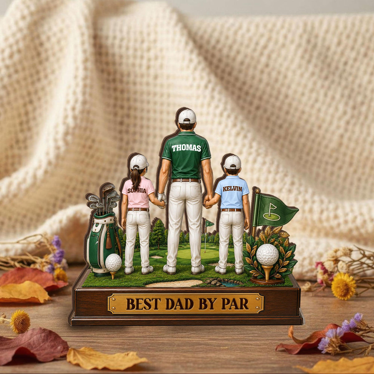 May include: A decorative golf-themed figurine featuring a father and two children on a golf course. The father wears a green shirt with "Thomas" on the back. The base reads "BEST DAD BY PAR". A golf bag, golf balls, and a green flag are also included.