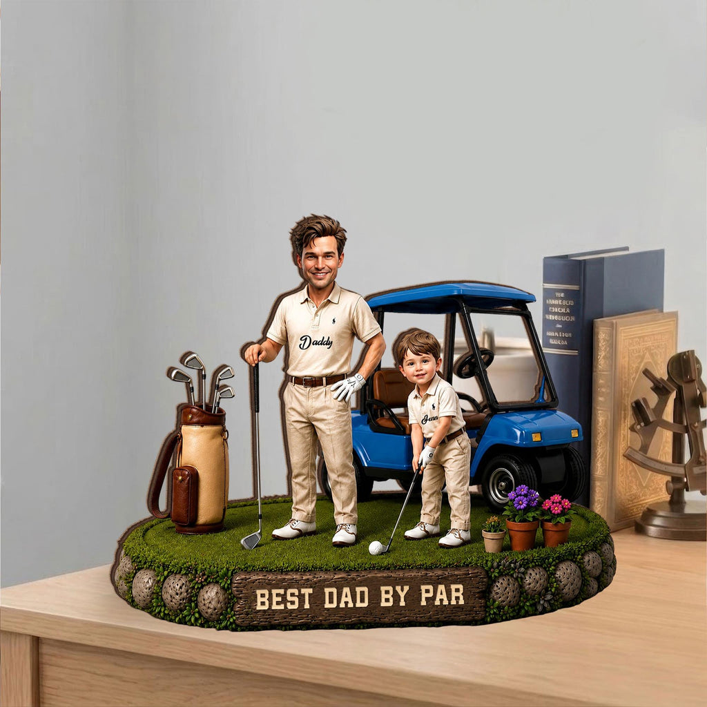 May include: A decorative figurine featuring a man and a child in golf attire, standing on a green, grassy base. A blue golf cart is behind them. The base has the text "BEST DAD BY PAR".