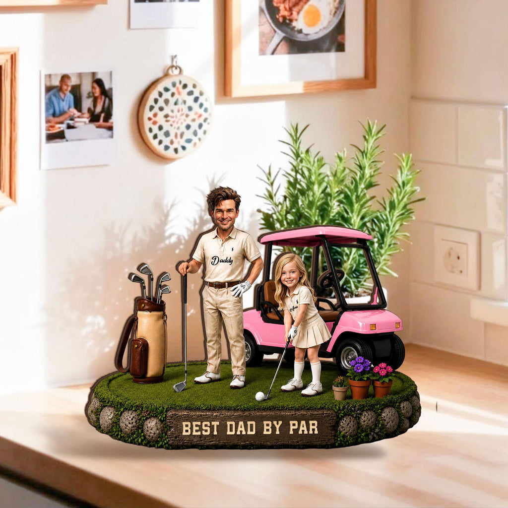 May include: A decorative figurine featuring a man and a girl on a golf course with a pink golf cart. The base reads "BEST DAD BY PAR". The man is holding a golf club and the girl is about to hit a golf ball. A golf bag and clubs are also present.