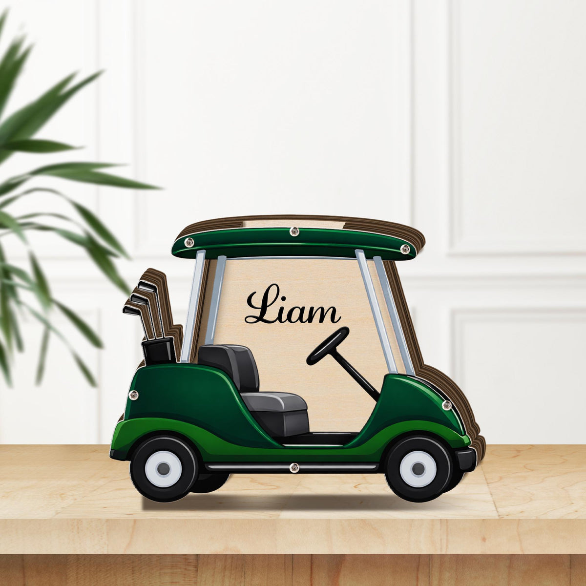 May include: A wooden golf cart-shaped frame in green and brown, with the name "Liam" in script. The cart has a black seat, steering wheel, and golf clubs. The frame is on a light wood surface.