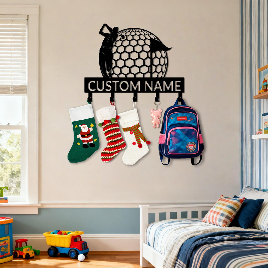 May include: Black metal wall-mounted organizer featuring a golfer silhouette and a golf ball design. Below, the text "CUSTOM NAME" is displayed. Includes hooks for hanging Christmas stockings and a backpack. The stockings are green, red, and white.