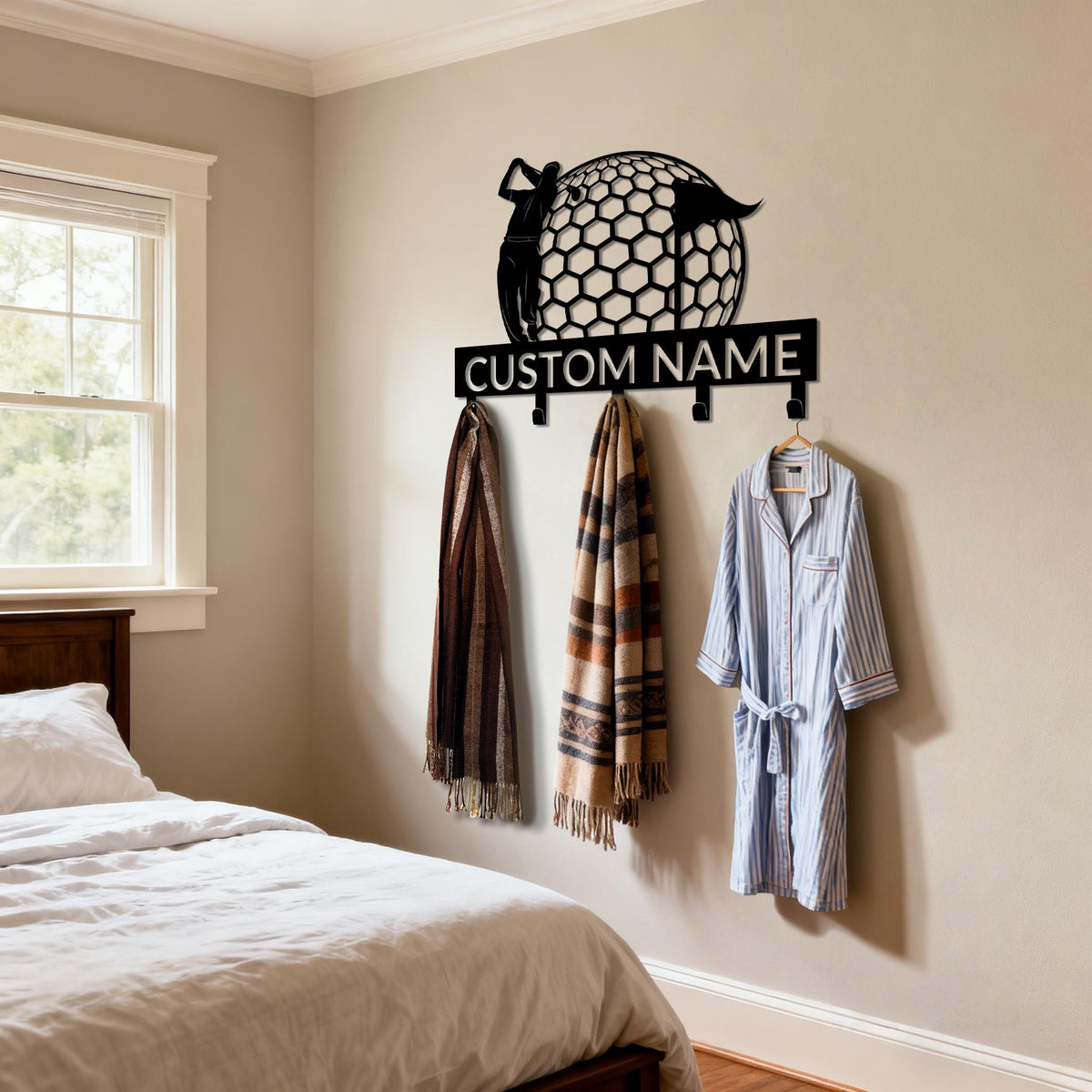 May include: A black metal golf-themed wall hook with the text "CUSTOM NAME". The design features a golfer and a golf ball. Three hooks hold a scarf, a patterned shawl, and a blue and white striped robe.