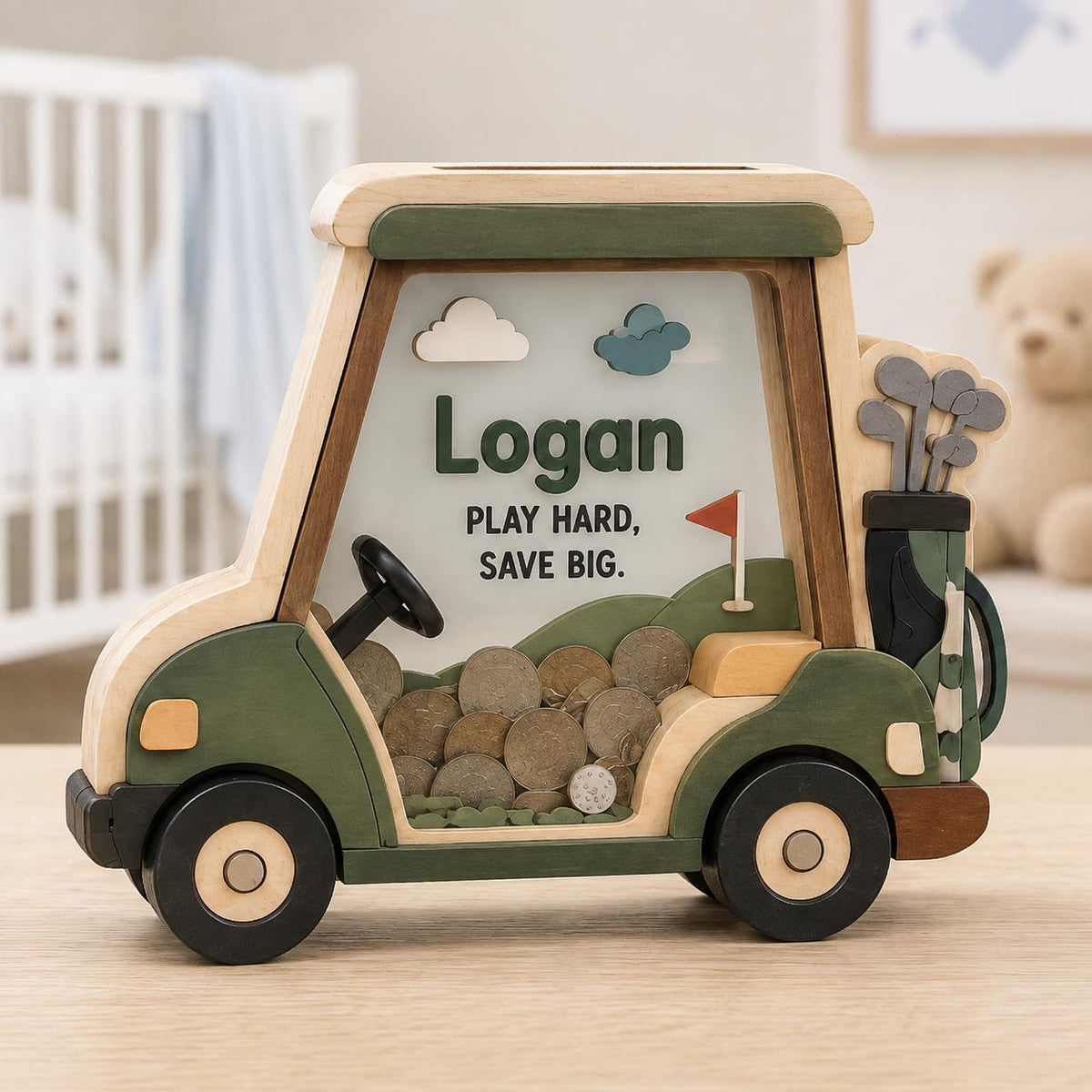 May include: A wooden piggy bank shaped like a golf cart, featuring a clear front panel filled with coins. The cart is painted in shades of green and tan, with the text "Logan" and "PLAY HARD, SAVE BIG." printed on the front, alongside a golf bag.