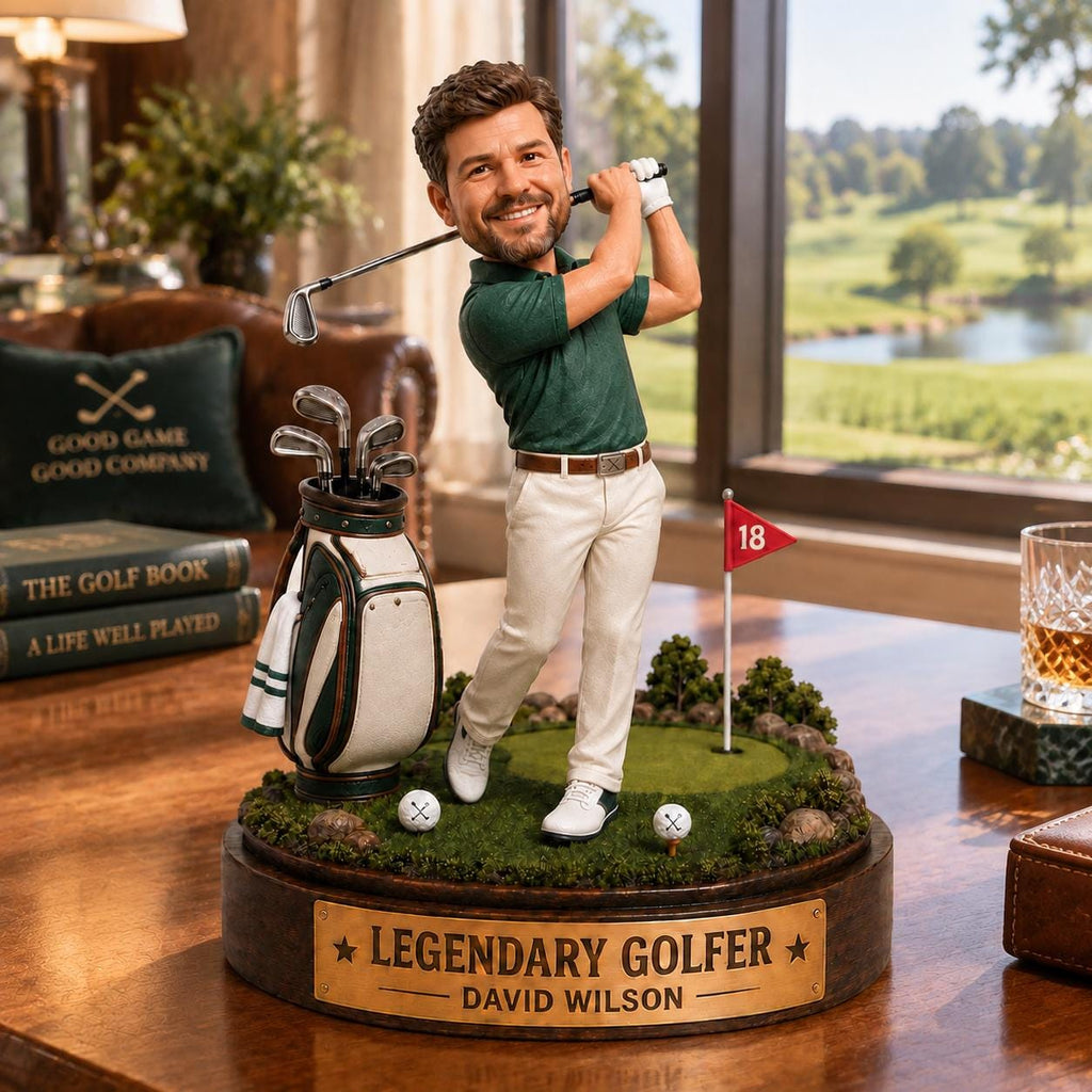 May include: A custom bobblehead figurine of a golfer in a green polo shirt and white trousers, swinging a golf club. The base features a golf bag, two golf balls, a red flag marked 18, and a plaque reading LEGENDARY GOLFER DAVID WILSON.