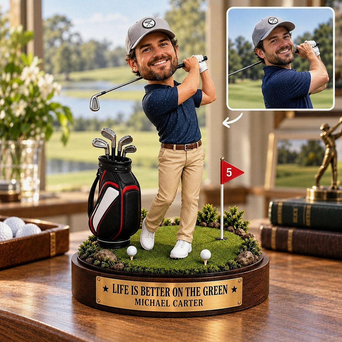 May include: A custom bobblehead figurine of a golfer wearing a grey cap, navy blue polo, and khaki pants, standing on a green base with a golf bag, a flag marked 5, and a plaque reading LIFE IS BETTER ON THE GREEN MICHAEL CARTER.