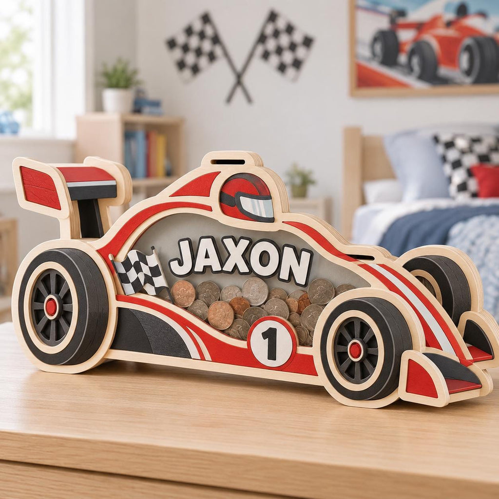 May include: A wooden race car shaped piggy bank featuring red, black, and white details with a clear acrylic side panel. The side displays the name JAXON in white letters, a checkered flag, and the number 1. The interior is filled with various coins.