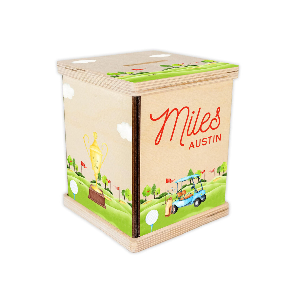 May include: A wooden golf-themed money box with a green, brown, and blue design. The box has a slot on the top for coins and a personalized inscription that reads "Miles AUSTIN".