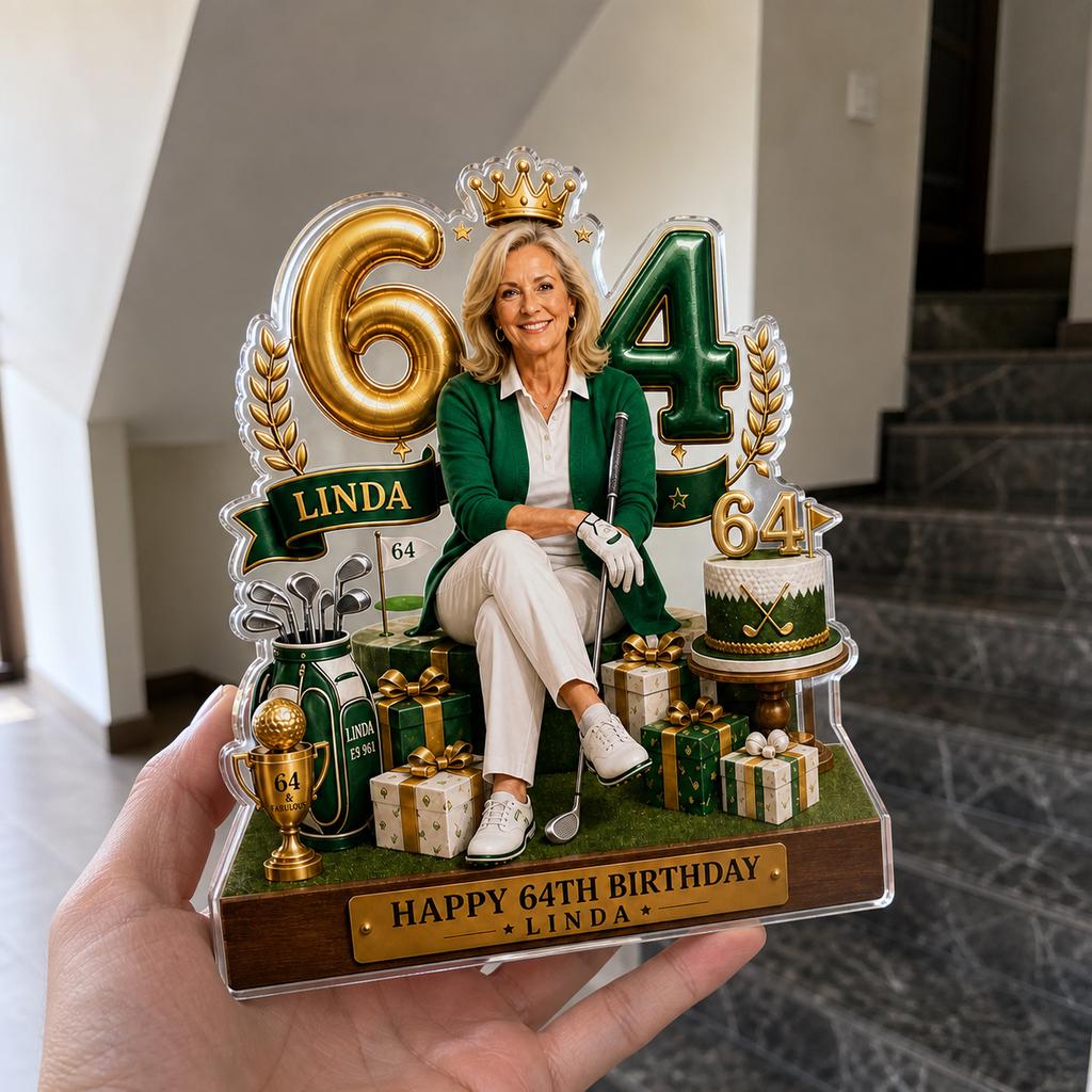 May include: A decorative acrylic birthday display featuring a central image of a woman in a green cardigan and white pants, surrounded by gold number 64, a golf bag, a cake, and gift boxes. The base includes a plaque reading HAPPY 64TH BIRTHDAY LINDA.