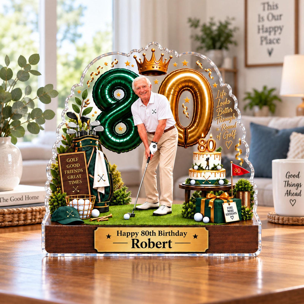 May include: A decorative acrylic display featuring a golfer, a green number 80 balloon, a gold number 80 balloon, a golf bag, a birthday cake, and a gift box. The base is wood with a plaque reading Happy 80th Birthday Robert. Text includes Life Looks Better Through a Round of Golf.