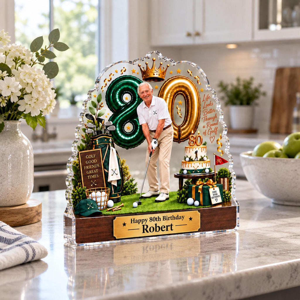 May include: A decorative acrylic display featuring a golfer, a green balloon shaped like an 8, a gold balloon shaped like a 0, a cake, and a golf bag. The base is wood-toned with a plaque reading Happy 80th Birthday Robert. Text includes Life Looks Better Through a Round of Golf.