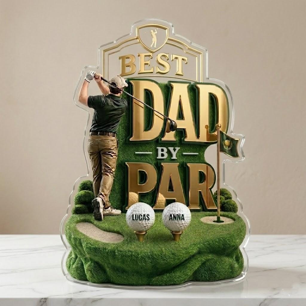 May include: A clear acrylic golf-themed trophy with the words "BEST DAD BY PAR" in gold lettering. The trophy features a golfer, golf balls, and a green golf course design. The names "Lucas" and "Anna" are on the golf balls.
