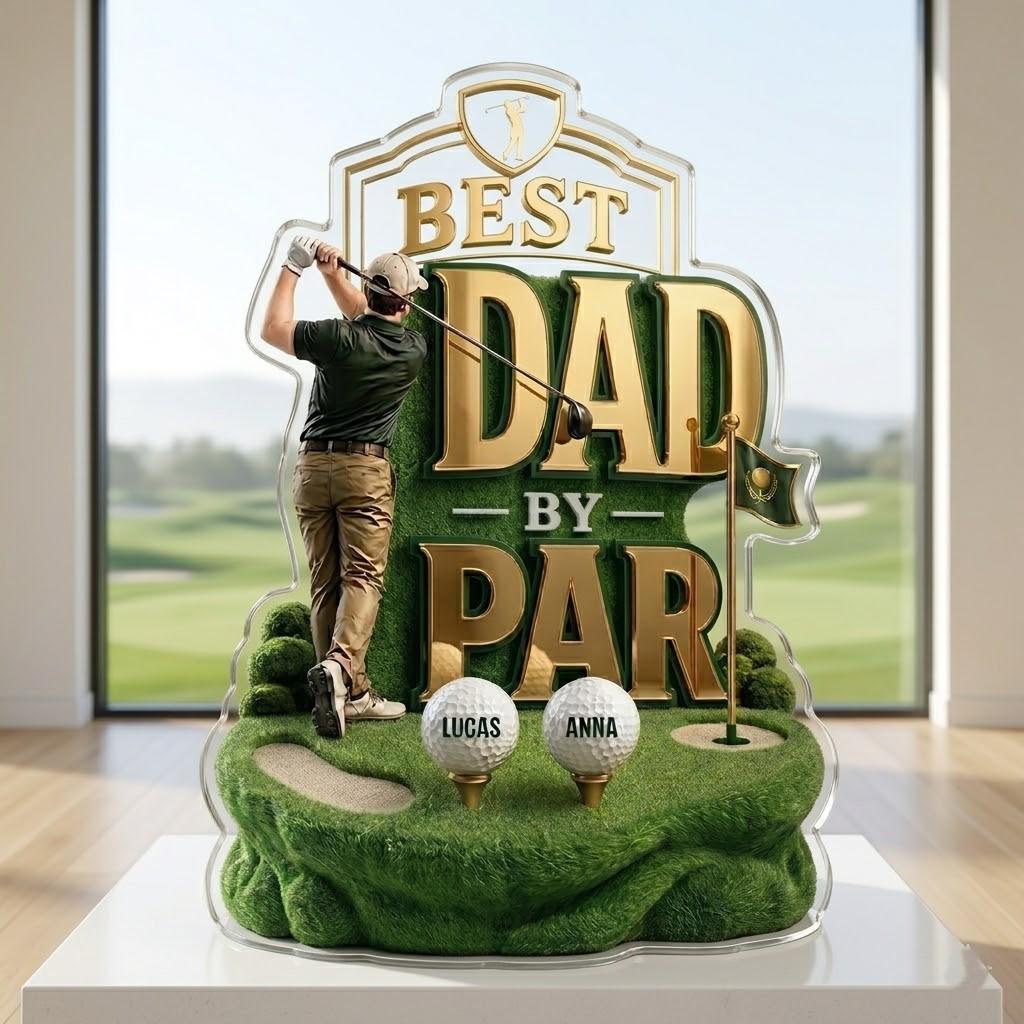May include: A golf-themed acrylic display with the text "BEST DAD by PAR". The design features a golfer, golf balls with names, and a green golf course scene. The display is on a white surface.