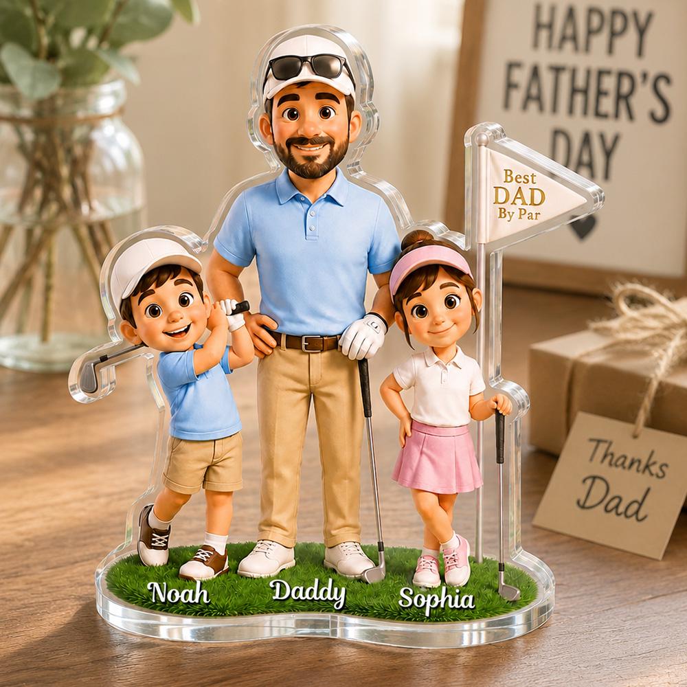 May include: A clear acrylic golf-themed figurine featuring a father and two children. The father wears a blue polo shirt and khaki pants. The children are dressed in golf attire. The base is green with the names "Noah", "Daddy", and "Sophia". A sign reads "Best Dad By Par".