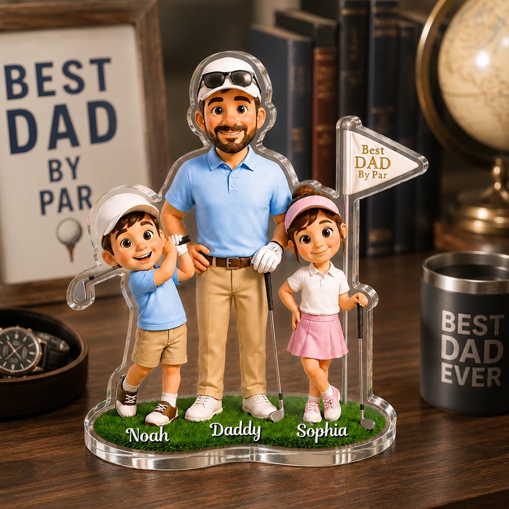 May include: A clear acrylic golf-themed family figurine featuring a father, son, and daughter. The father wears a blue polo shirt and khaki pants, while the children wear golf attire. The base is green with the names "Noah", "Daddy", and "Sophia". A sign reads "Best Dad By Par".