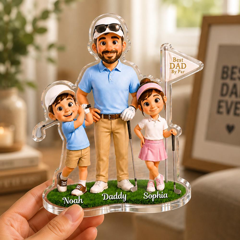 May include: A clear acrylic golf-themed family figurine featuring a father, son, and daughter. The father wears a blue polo shirt and khaki pants, while the children wear golf attire. The base has the names "Noah", "Daddy", and "Sophia". A flag reads "Best Dad By Par".