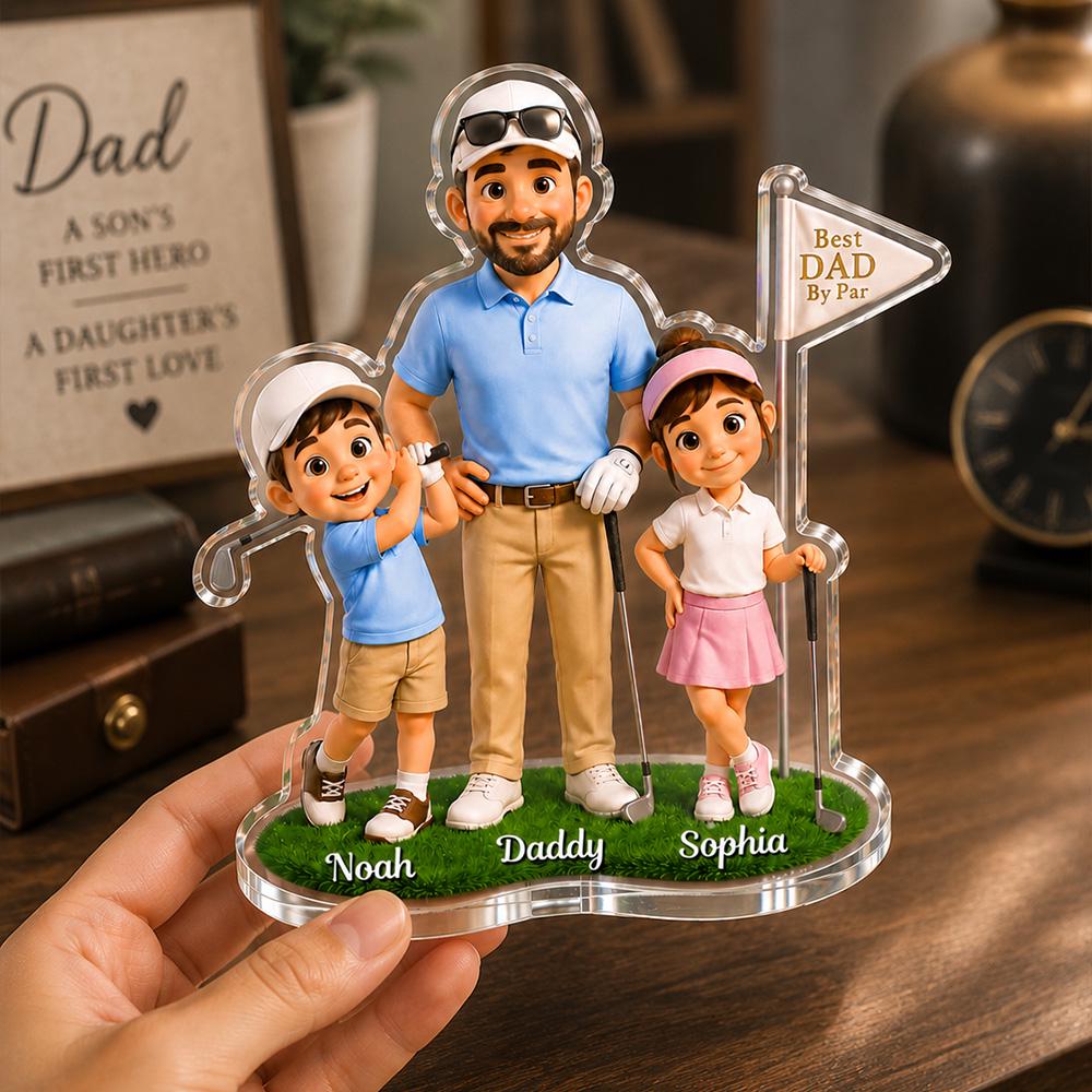 May include: A clear acrylic golf-themed figurine featuring a father and two children. The father wears a blue polo shirt and khaki pants. The children are dressed in golf attire. The base is green with the names "Noah", "Daddy", and "Sophia". The text "Best Dad By Par" is also visible.