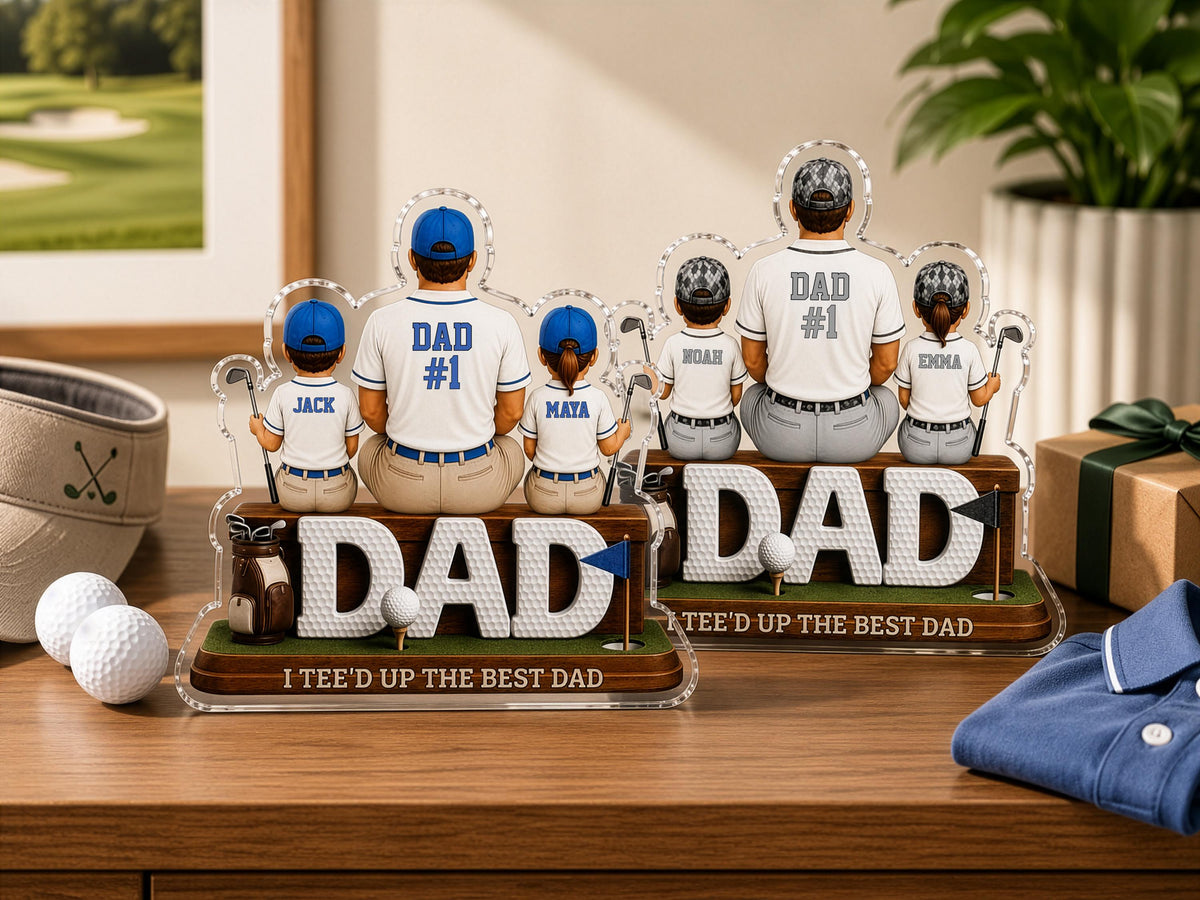 May include: Two custom acrylic tabletop displays featuring cartoon-style figures of a parent and children dressed in baseball uniforms. The figures sit on wooden bases labeled DAD with the text I TEE'D UP THE BEST DAD. One display shows DAD #1.