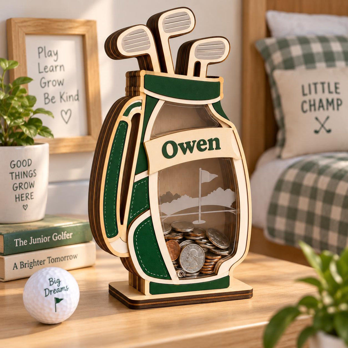 May include: A wooden golf bag shaped piggy bank with a clear front panel, filled with assorted coins. The design features dark green accents, a light wood finish, and the name Owen printed on a central banner. Two golf clubs are visible at the top.