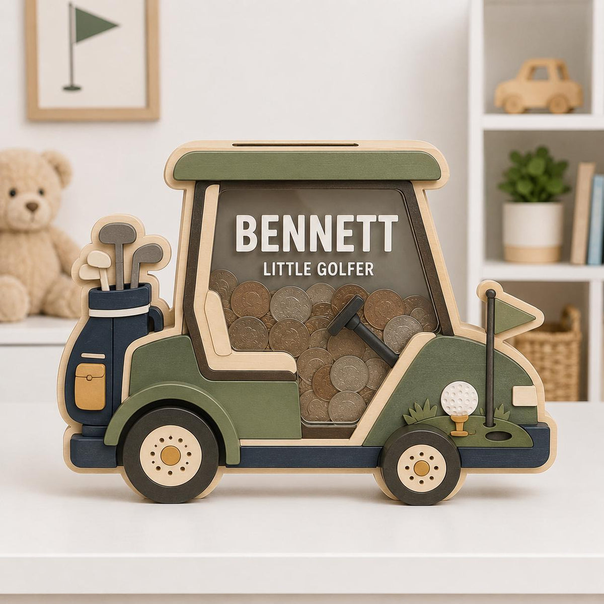 May include: A wooden golf cart-shaped piggy bank featuring a clear front panel filled with coins. The cart is painted in shades of green, navy blue, and cream, with the text BENNETT LITTLE GOLFER printed on the front. A golf bag with clubs is attached to the back.