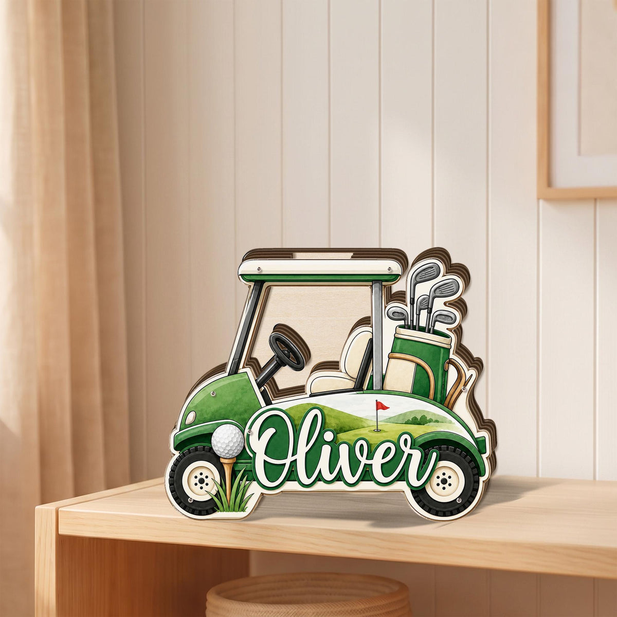 May include: A layered wooden cutout of a green golf cart featuring the name Oliver in white script. The design includes a golf bag with clubs, a steering wheel, a white golf ball on a tee, and a background illustration of a golf course.