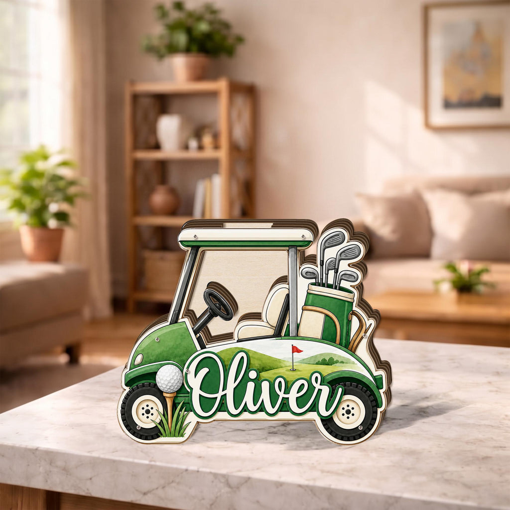 May include: A layered wooden cutout of a golf cart featuring a green and white color scheme, a golf bag with clubs, a golf ball on a tee, and the name Oliver written in white cursive script across the side of the vehicle body.