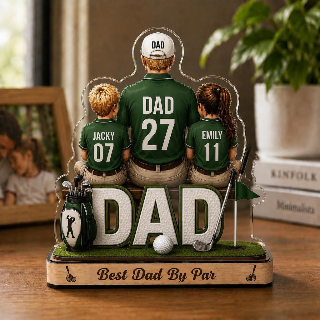 May include: A decorative golf-themed figurine featuring a father and two children. The father wears a green golf shirt with "DAD 27" on the back. The children's shirts say "Jacky 07" and "Emily 11". The base reads "Best Dad By Par".
