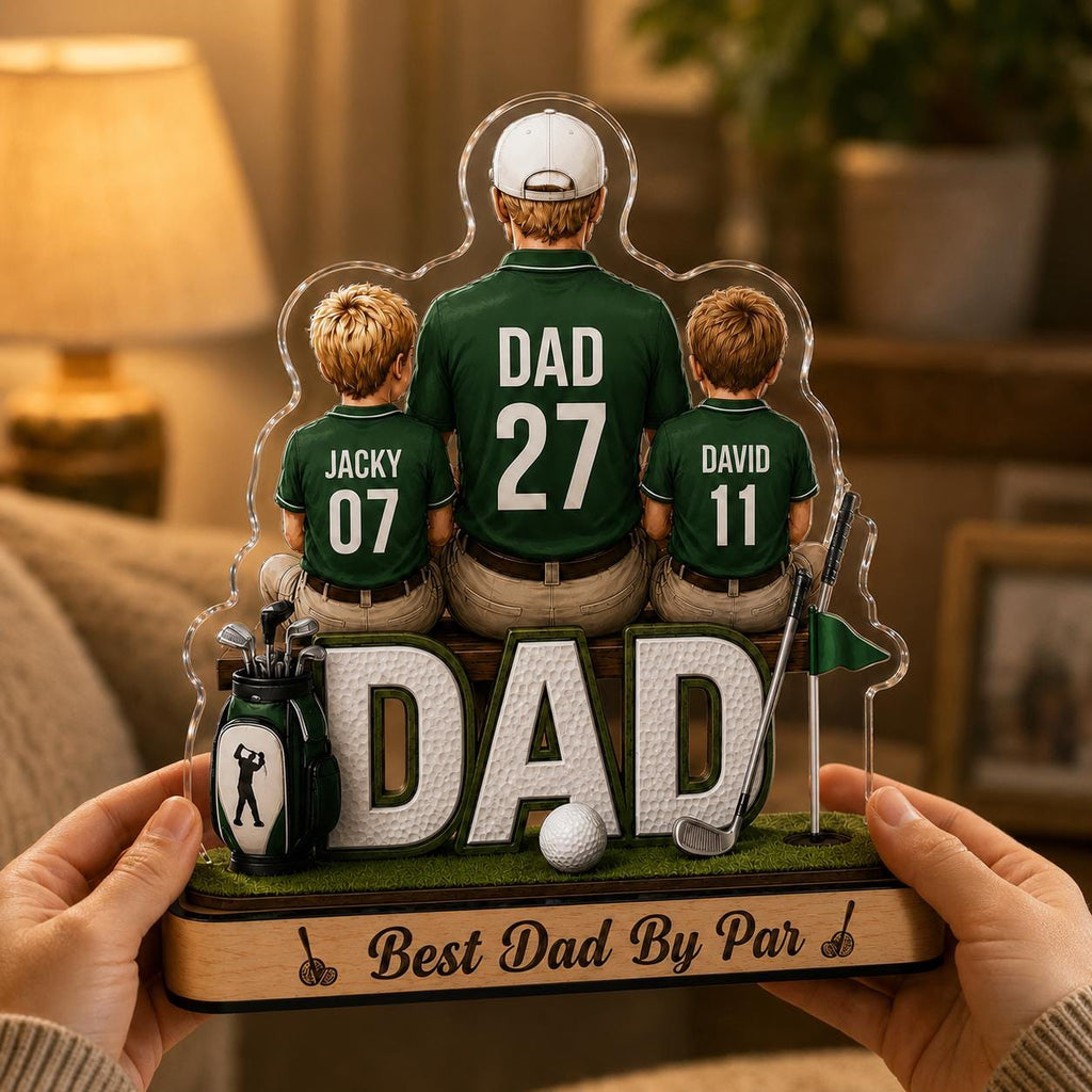 May include: A personalized golf-themed acrylic plaque featuring a father and two children. The figures are wearing green shirts with the word "DAD" and numbers. The base reads "Best Dad By Par" with golf-related imagery.