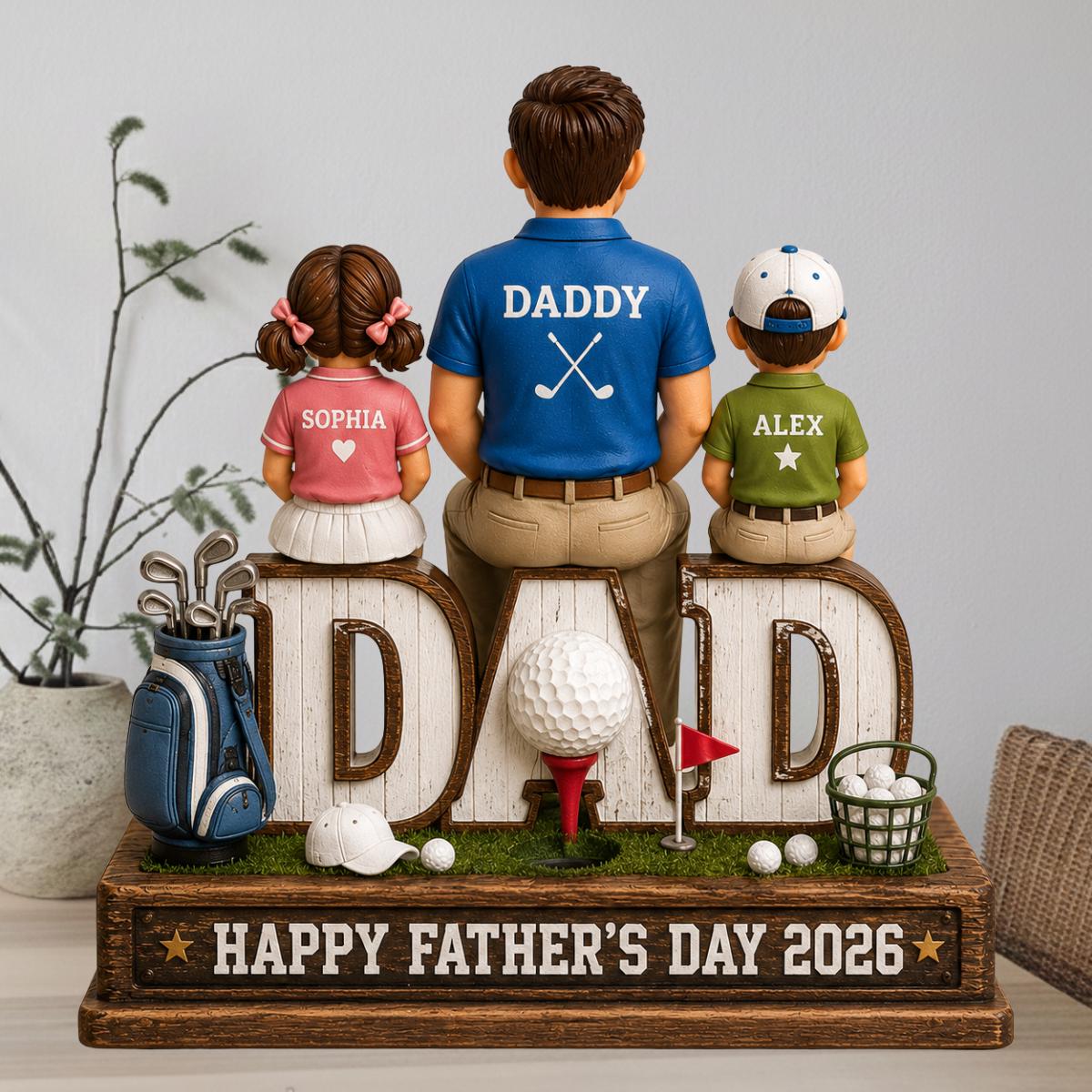 May include: A decorative Father's Day figurine featuring a father and two children sitting on the letters of the word "DAD". The father wears a blue shirt with "DADDY" and crossed golf clubs. The base reads "HAPPY FATHER'S DAY 2026". Golf accessories are included.