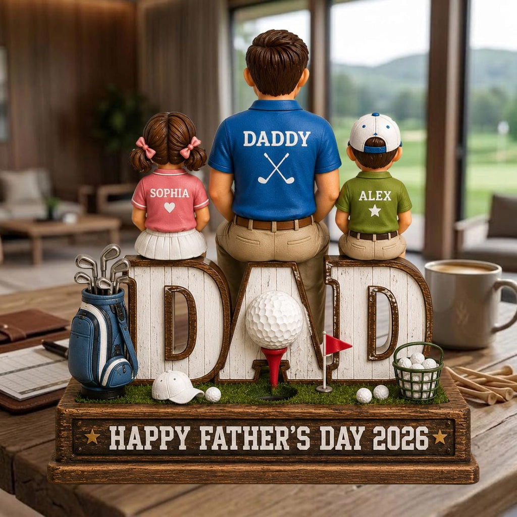 May include: A Father's Day golf-themed figurine featuring a father and two children. The word "DAD" is prominently displayed, with a golf ball and accessories. The base reads "HAPPY FATHER'S DAY 2026". The children's shirts have the names "Sophia" and "Alex".