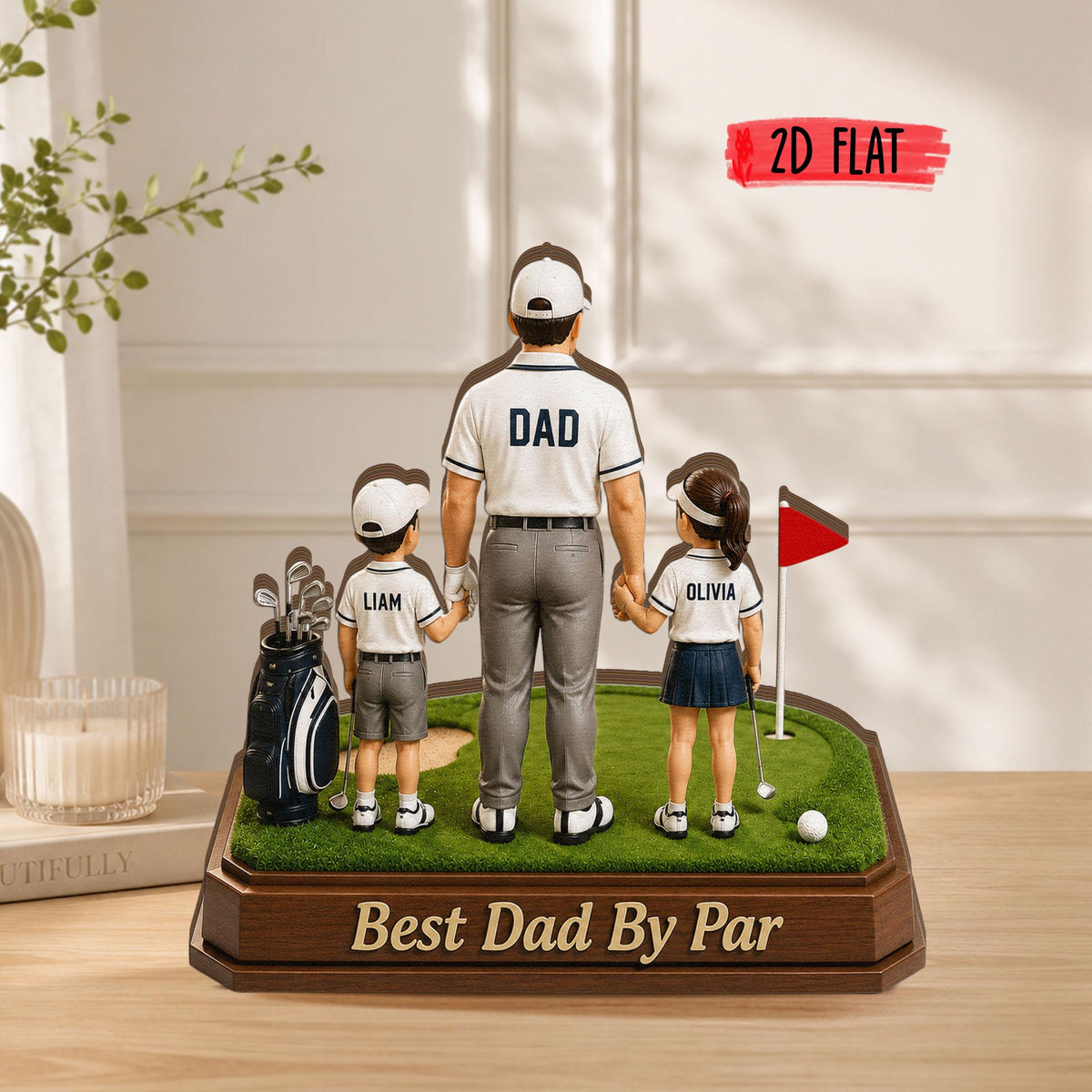May include: A decorative figurine of a father and two children on a golf course. The father's shirt says "DAD". The base reads "Best Dad By Par". A golf bag and flag are also present. The children's shirts have the names "Liam" and "Olivia".