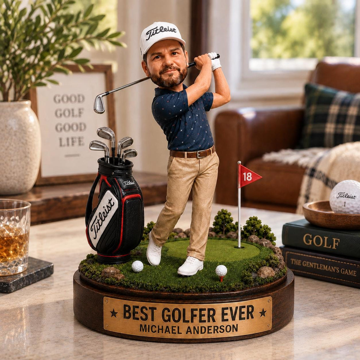 May include: A custom bobblehead figurine of a golfer wearing a white Titleist cap, navy patterned polo, and khaki pants, swinging a club. The figure stands on a circular base with a green putting surface, a golf bag, and a plaque reading BEST GOLFER EVER.