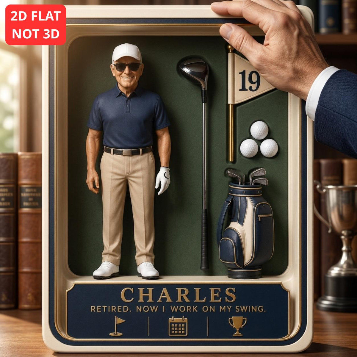 May include: A 2D flat display box featuring a figure of a golfer in a navy polo and tan pants, a golf club, a flag with the number 19, three golf balls, and a golf bag. The text reads CHARLES RETIRED. NOW I WORK ON MY SWING. with golf icons.