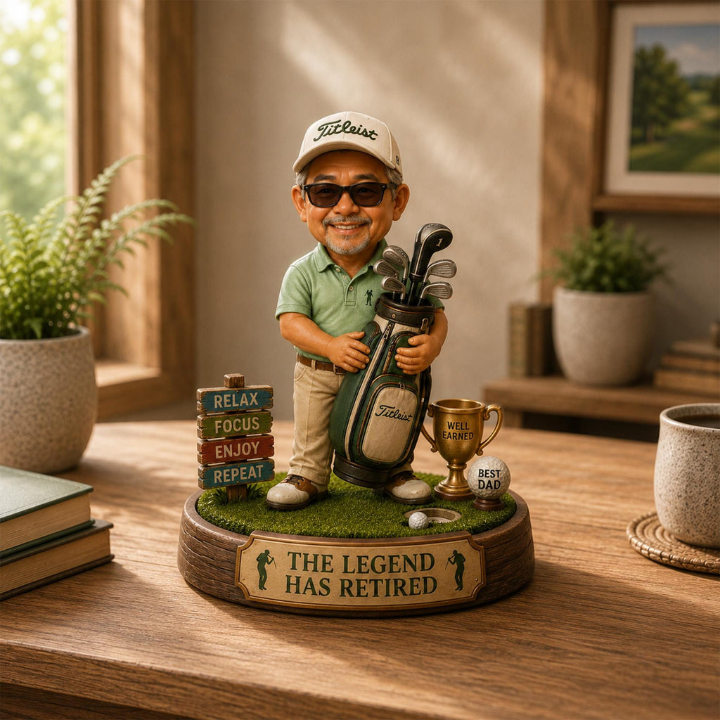 May include: A figurine of a golfer wearing a Titleist cap, sunglasses, and a green polo shirt, holding a golf bag. The base features a sign with the text RELAX, FOCUS, ENJOY, REPEAT, a gold trophy, a golf ball labeled BEST DAD, and THE LEGEND HAS RETIRED.