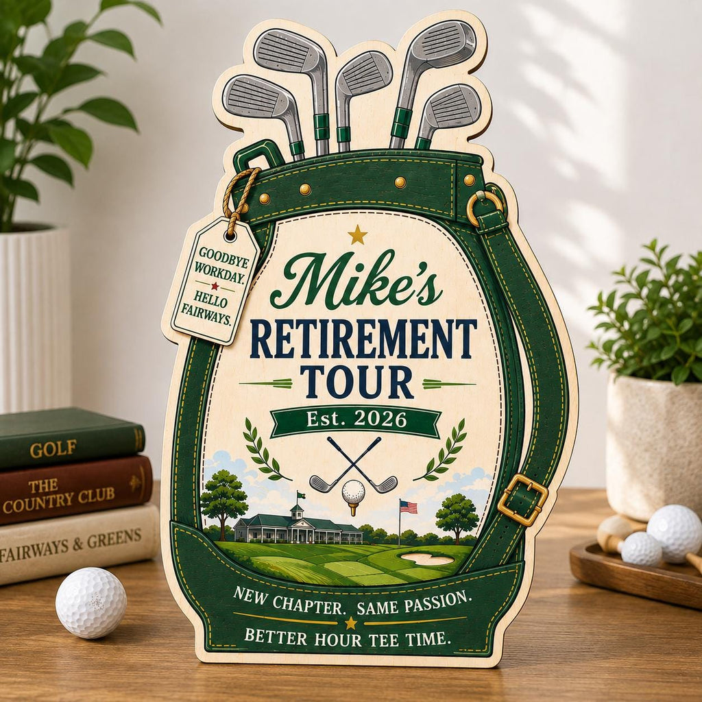 May include: A decorative wooden sign shaped like a golf bag with green trim, featuring the text "Mike's RETIREMENT TOUR Est. 2026", "GOODBYE WORKDAY. HELLO FAIRWAYS.", "NEW CHAPTER. SAME PASSION.", and "BETTER HOUR TEE TIME." It includes illustrations of golf clubs.