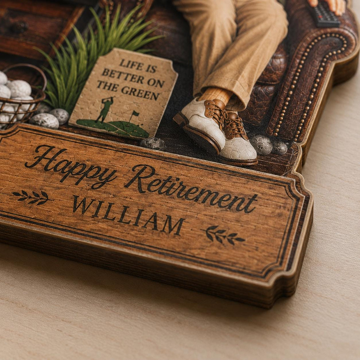 May include: A wooden retirement plaque featuring the text Happy Retirement WILLIAM with decorative leaf accents. The design includes a printed image of a person in tan trousers and golf shoes sitting on a leather chair, with a sign reading LIFE IS BETTER ON THE GREEN and a small basket of golf balls.