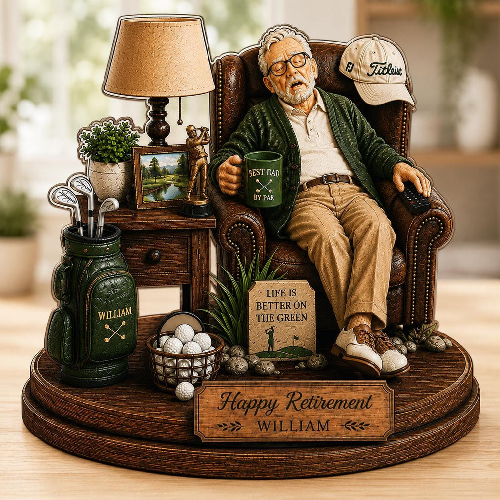 May include: A decorative figurine featuring an older person sleeping in a brown leather armchair, holding a green mug labeled 'BEST DAD BY PAR'. Includes a golf bag, a basket of golf balls, a lamp, and a sign reading 'Happy Retirement WILLIAM'.