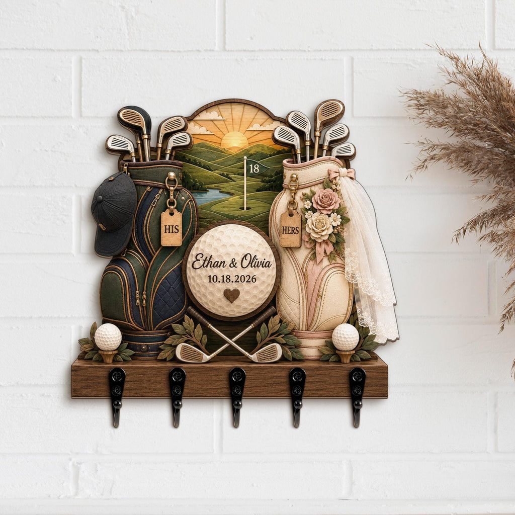 May include: A wooden wall-mounted key holder featuring two golf bags, one dark green and one cream, with a central golf ball displaying the text Ethan & Olivia 10.18.2026. The design includes golf clubs, a cap, floral accents, and five black hooks.