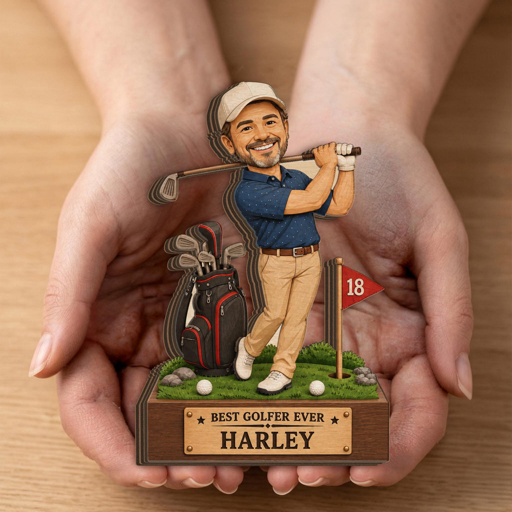 May include: A layered wooden cutout figurine of a golfer wearing a beige cap, blue polo shirt, and khaki pants, holding a golf club. Beside the figure is a golf bag, a red flag with the number 18, and a base labeled BEST GOLFER EVER HARLEY.