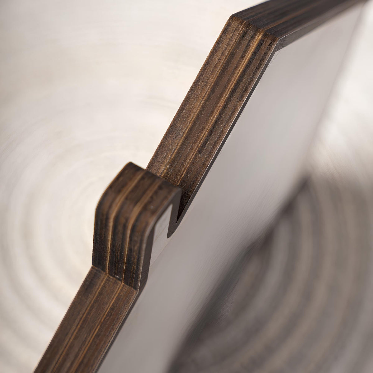 May include: A close-up view of a flat, rectangular object constructed from layered plywood. The edges reveal the dark, horizontal grain of the stacked wood veneers, while the main surface is a smooth, light-colored, solid material.