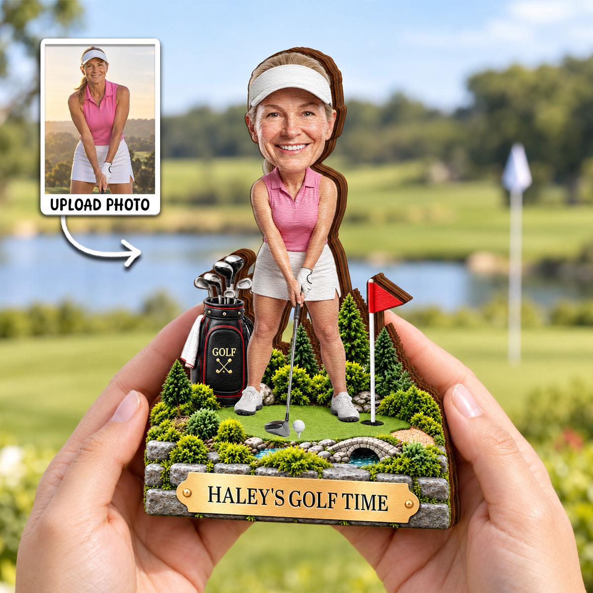May include: A custom bobblehead figurine featuring a person in a pink polo shirt and white skirt holding a golf club on a green course. The base includes a golf bag, a red flag, a stone bridge, and a gold plaque reading HALEY'S GOLF TIME.