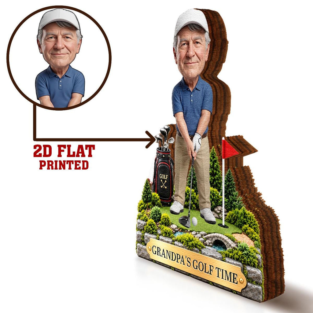 May include: A 2D flat printed golf-themed display featuring a caricature of a man in a blue polo shirt and khaki pants. The base includes a golf bag, a green, a red flag, and a stone wall plaque with the text "GRANDPA'S GOLF TIME" in gold.