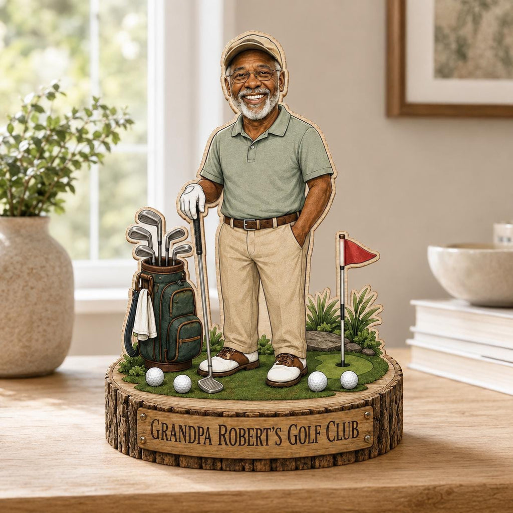 May include: A wooden tabletop display featuring a smiling older golfer in a green polo shirt and tan trousers, standing next to a golf bag with clubs, a red flag, and golf balls. The base is engraved with the text, "GRANDPA ROBERT'S GOLF CLUB."