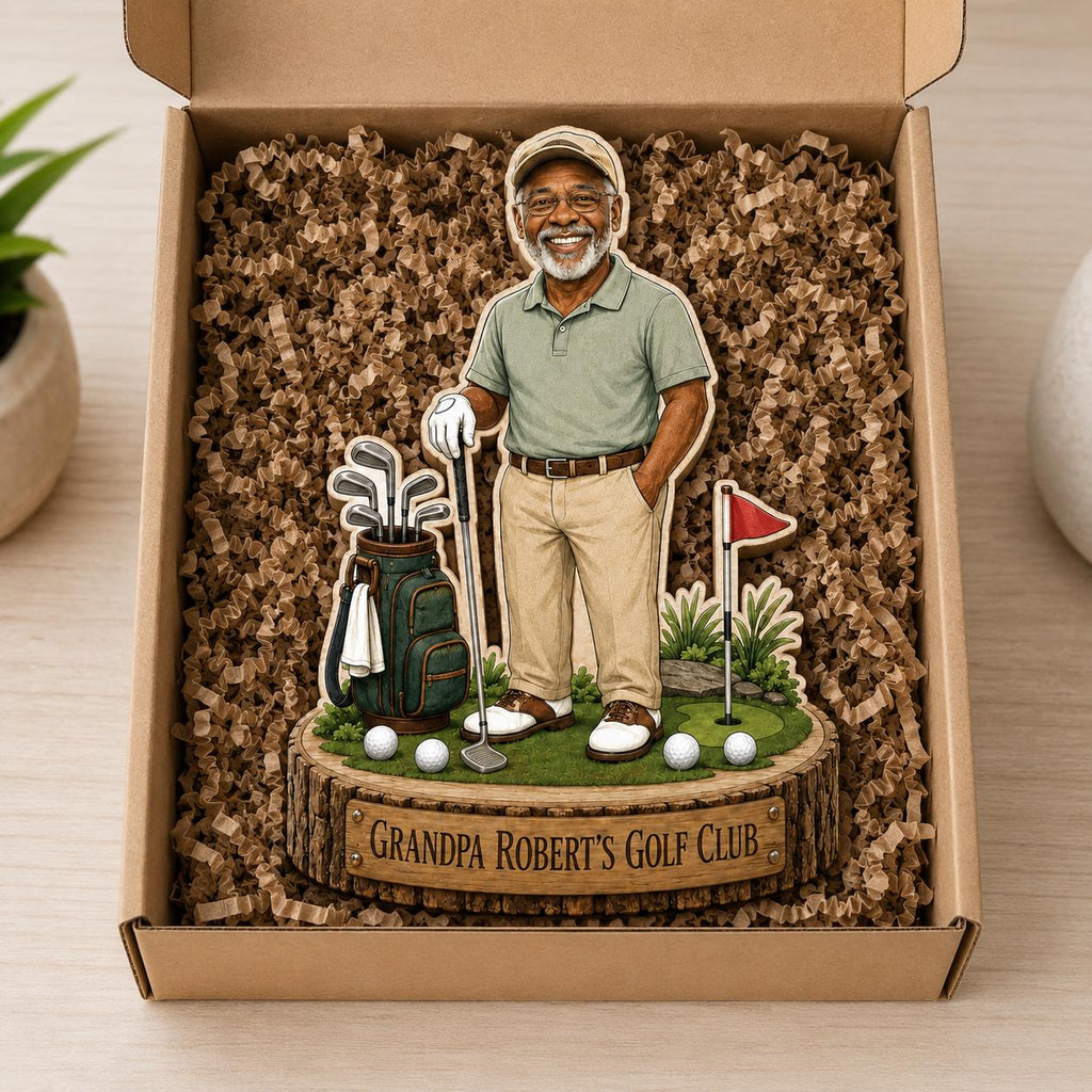 May include: A decorative wooden display featuring a cartoon-style older golfer in a light green polo and khaki pants, standing next to a golf bag and a flag on a green base. The base has a plaque that reads GRANDPA ROBERT'S GOLF CLUB.