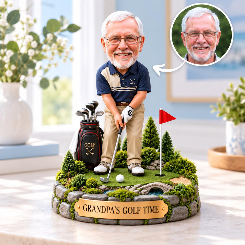 May include: A custom bobblehead figurine of an older man with glasses wearing a navy and beige polo shirt and khaki pants, holding a golf club on a miniature green with a golf bag, a red flag, and a plaque that reads GRANDPA'S GOLF TIME.