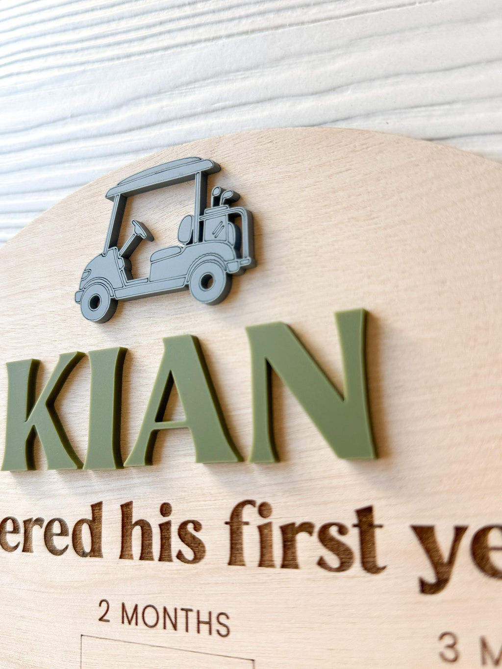 close-up detail of custome acrylic name and golf cart accent on wood milestone photo board.