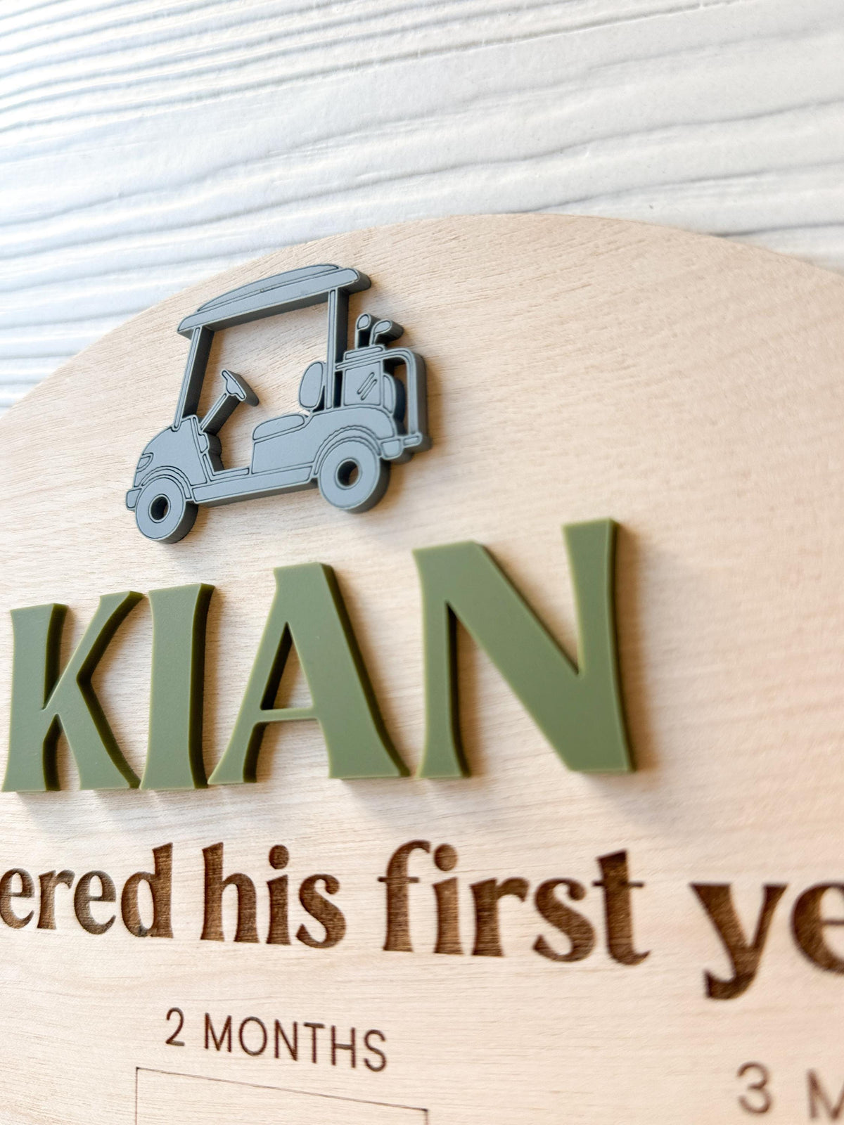 close-up detail of custome acrylic name and golf cart accent on wood milestone photo board.