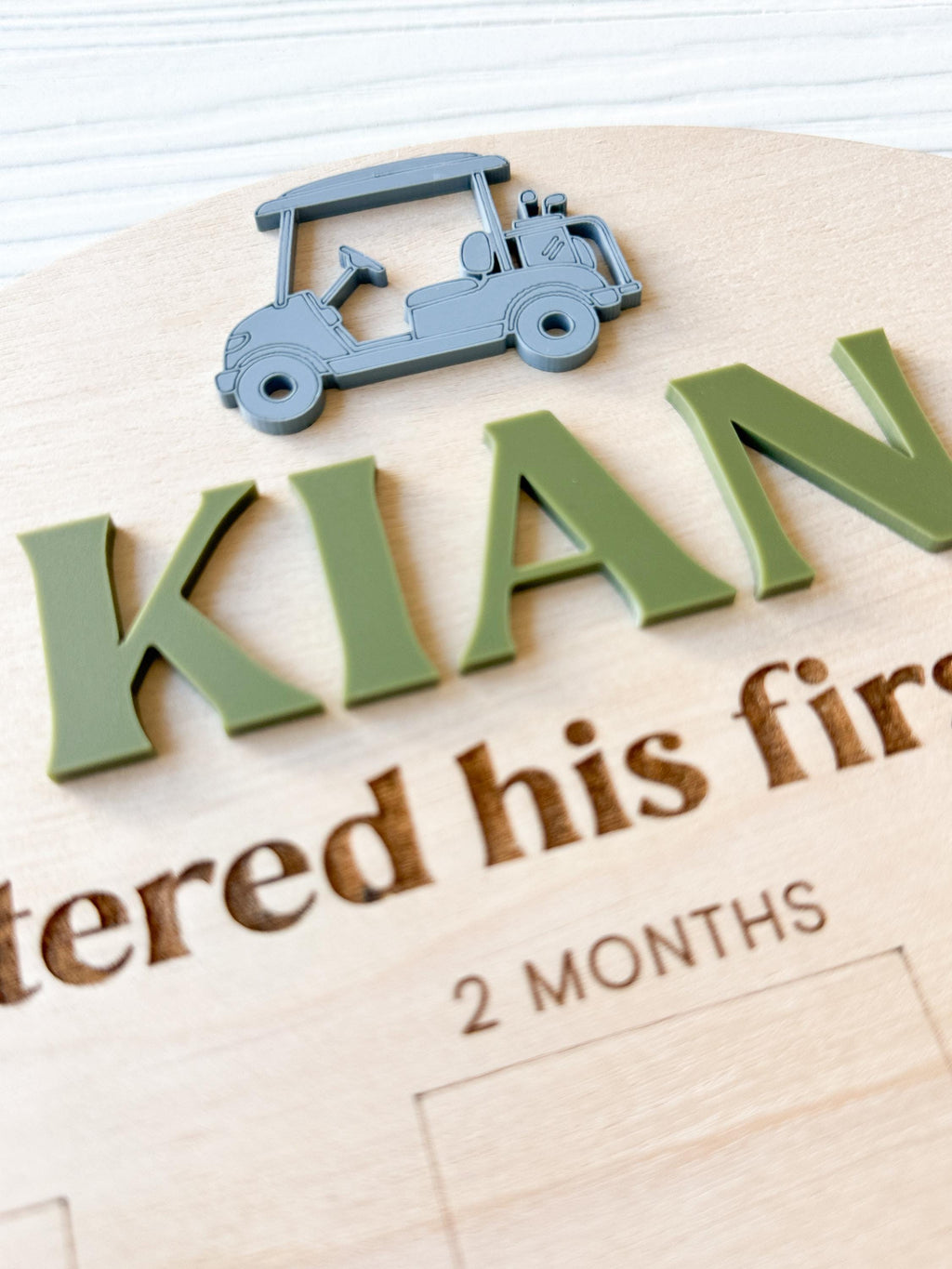 close-up detail of custome acrylic name and golf cart accent on wood milestone photo board.