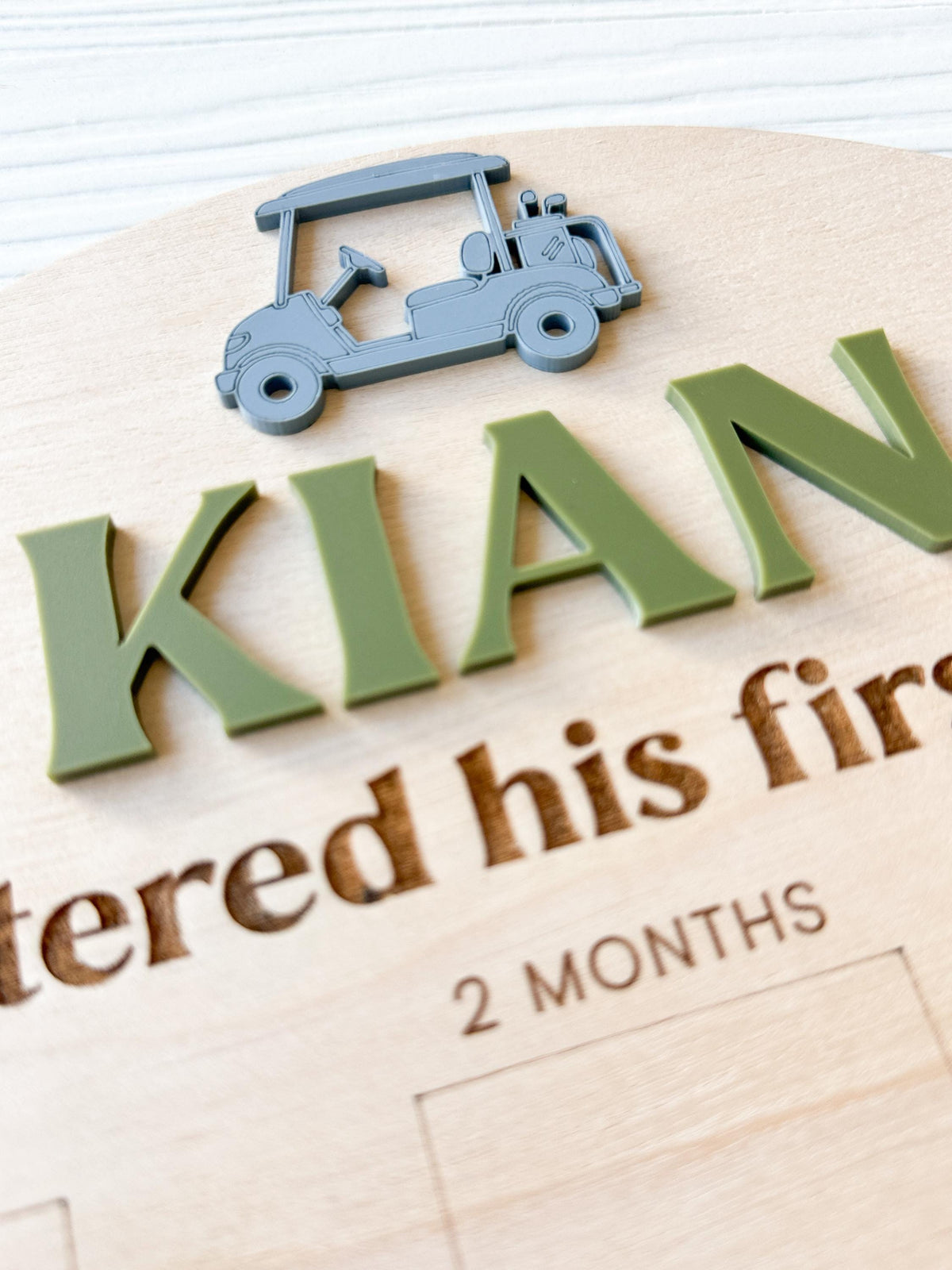 close-up detail of custome acrylic name and golf cart accent on wood milestone photo board.